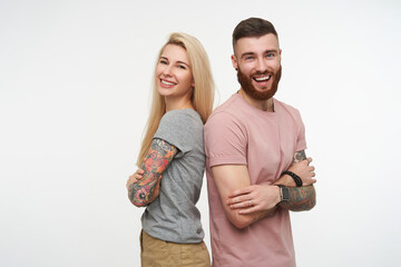 Studio photo of lovely glad couple keeping hands crossed on their chests and laughing happily while...