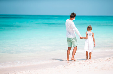 Little girl and happy dad having fun during beach vacation