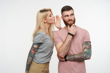 Positive young pretty bearded guy holding his chin with raised hand and looking dreamily upwards...