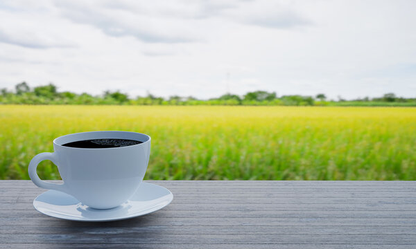 Black coffee in a white coffee mug and saucer on the table. Wooden floor. The background is a picture of a blurred cornfield and golden brown rice fields. 3D Rendering