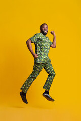 Fototapeta na wymiar Joyful black man jumping up over yellow background