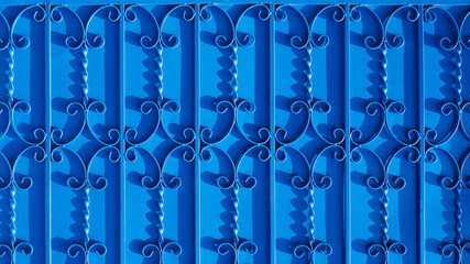 Sunlight and shadow on surface of wrought-iron elements pattern on vintage blue metal gate door background, exterior architecture concept