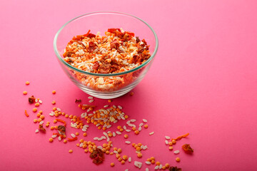 Glass jar with yellow lentils on a pink background.