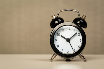 Black retro alarm clock with bells on a wooden table, daily routine concept.