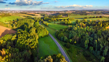 Idyllic German landscape shot from above in early morning sunlight: meadows and forests with blue...