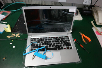 laptop is on the table and has a blue anti-static cable.