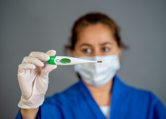 COVID-19 Symptoms and prevention. Doctor with surgical mask holding thermometer. Temperature check.
