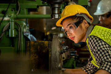 Female worker wearing hard hat are working in industrial plants that have machines.