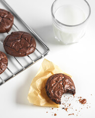bited dark chocolate cookies on baking tray serving with a glass of milk. concept of delicious homemade dessert or snack good for kids and party.