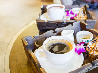 Hot black coffee set with cookies and orchids decorated on the table