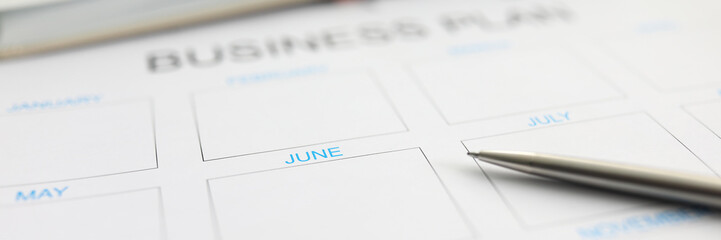 Silver pen lying over paper monthly plan for june