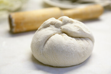 The dough and rolling pin are on the table. Food preparation.