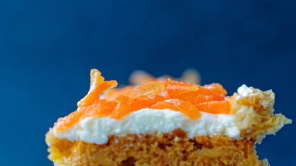 A close view of a piece of Swiss carrot cake. Grated carrots are on top of a delicate cream biscuit. Culinary concept.