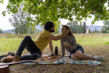 A couple having a picnic in the middle of nature. Having breakfast and enjoying the day.