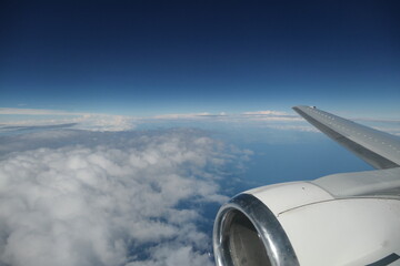 Fototapeta na wymiar avion vue hublot ciel bleu et nuages en bas