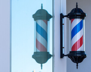 Rotary cylinder of a barber shop and its reflection in the glass of a window