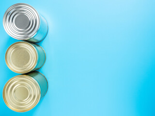 Food stocks for the duration of quarantine and isolation in the coronavirus and flu pandemic. Canned food in tin cans, isolated on a blue background, close-up, mockup, copyspace. Donation food
