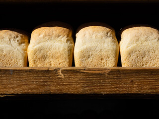 Golden, crisp, fresh bread on the wooden counter of a bakery or store. Homemade country bread,...