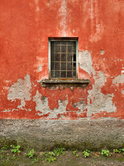 Ventana con reja sobre pared naranja desgastada en Gaeta, Nápoles, Italia