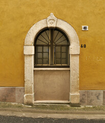 Fototapeta premium Puerta tapiada a ventana en Gaeta, Nápoles, Italia sobre pared ocre