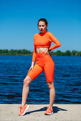 Young athletic girl does physical exercises on the banks of the Volga River