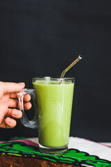 A glass of green healthy smoothie with spinach banana and orange lifestyle hand metal straw eco vegan