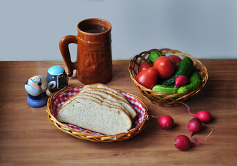 Fototapeta na wymiar A mug, a basket with bread, a basket with vegetables on the table