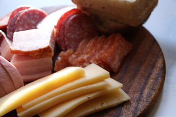 Sliced meat on a wooden stand. Sliced meat and cheese on a wooden board. A lot of different meat.