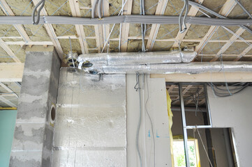 Fototapeta premium Renovating house indoors with air ventilation system, glass wool insulated ceiling, isolated electric wires, water pipes of radiant floor heating system, chimney breast plastering and wall layers.
