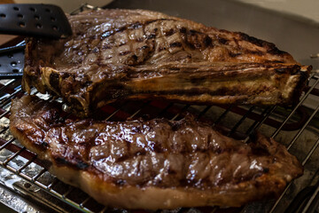 T-Bone Steak on an Electric Grill being taken with Tongs