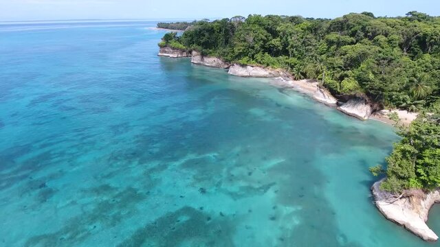Forward Flying Aerial View of Escudo Island with Tan Cliffs, White Sand Beaches, Tropical Thick Jungle, Clear Light Blue Water with Coral Reefs Showing
