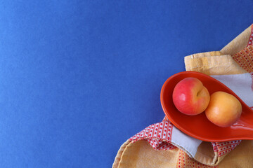 Apricots on a blue background with place for text. Towel, apricots in an orange tray on a blue background with place for text and design.