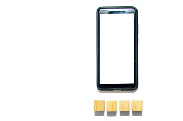 Wooden cubes and smartphone on a white background. The smartphone lies to the right under it four wooden cubes together and with a distance. There is a place for text