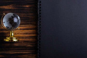 Glass globe on a black matte notebook on a wooden background