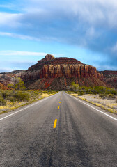 The road running through the dry prairie and rests on the red mountain.