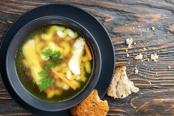 Chicken noodle soup and herbs in a plate on wooden boards, top view. Healthy homemade food concept.