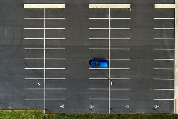 Top view on an empty parking lots with one blue car. Aerial view of car park. © vladim_ka