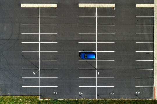 Top view on an empty parking lots with one blue car. Aerial view of car park.
