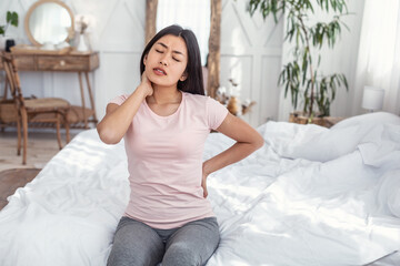 Woman Having Pain In Back And Neck Sitting In Bed