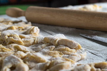 kitchen table. Sprinkled with flour. On it are dough products. Brushwood. Close-up