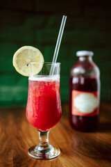 Fresh strawberry smoothie on the table with glass bottle in the background