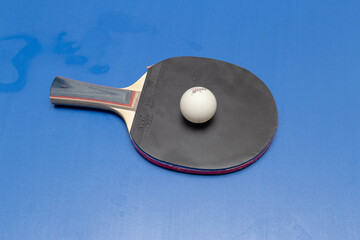 close-up of a ball and racket for table tennis on a blue table