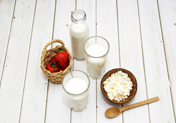 Kefir, milk, yogurt in bottle and blue glasses on white background whith strawberry and cocktail straws.
