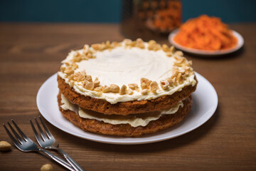 Carrot cake, hazel nuts and grated carrot on the wooden table