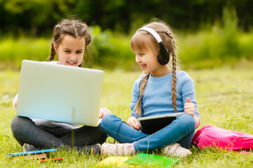 Two beautiful sisters do their homework during quarantine. Children use gadgets for learning. Education, distance learning, home schooling during quarantine