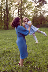 mother and daughter in a blue dress are played in the spring