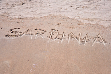 Sardinia sign written in sand on a famous Pelosa beach in Sardinia, Italy.