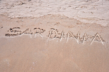 Sardinia sign written in sand on a famous Pelosa beach in Sardinia, Italy.