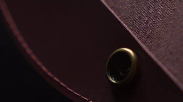 Close Up Woman Fashion Genuine Leather Texture Burgundy Bag Gold Metal Handcrafted Backstich Motion Shots Acsessories Clasp and Belt Details Concept Macro Stich on a Black Background 