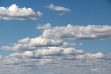Obraz premium White fluffy clouds on a background of blue sky in summer. The concept of weather and climate.